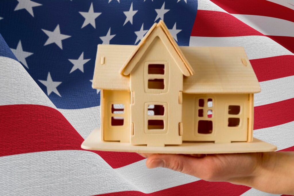 A miniature house model with an American flag in the background, symbolizing veterans and home ownership, emphasizing Veteran home buying resources.